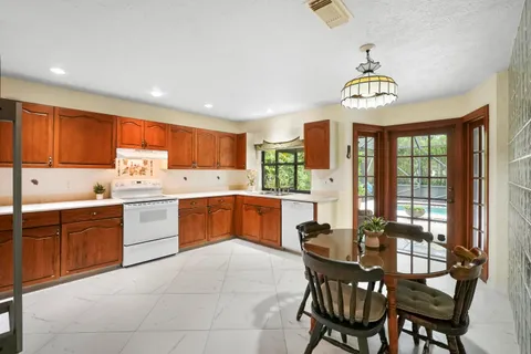 a kitchen with a refrigerator a sink dishwasher a dining table and chairs with wooden floor