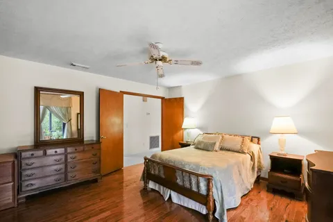 a bedroom with a bed and a dresser with wooden floor
