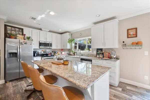 a kitchen with stainless steel appliances granite countertop a sink a stove counter space and refrigerator