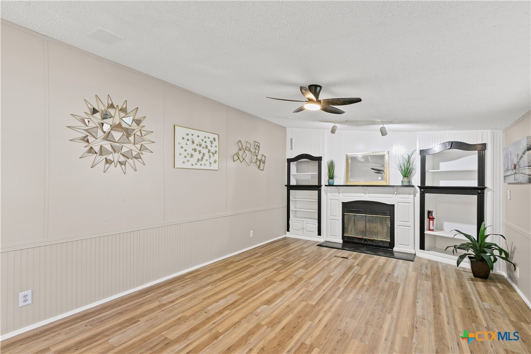 113 Austin Street Gatesville, TX 76528 - Photo 7 of 24 wooden floor in an empty room with a fireplace