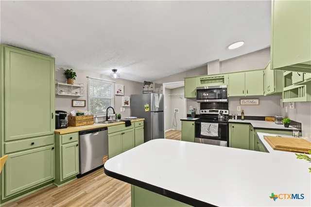 a kitchen with stainless steel appliances a stove top oven a sink dishwasher and a refrigerator