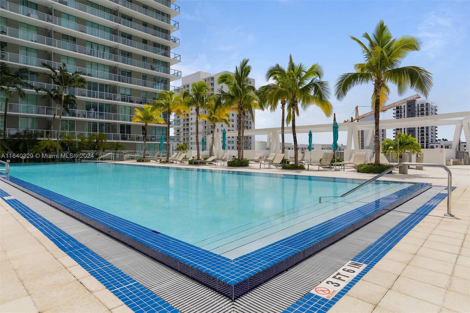 1111 Southwest 1st Avenue, Unit 3014N Miami, FL 33130 - Photo 18 of 36 a view of a swimming pool with a lawn chairs and palm tree