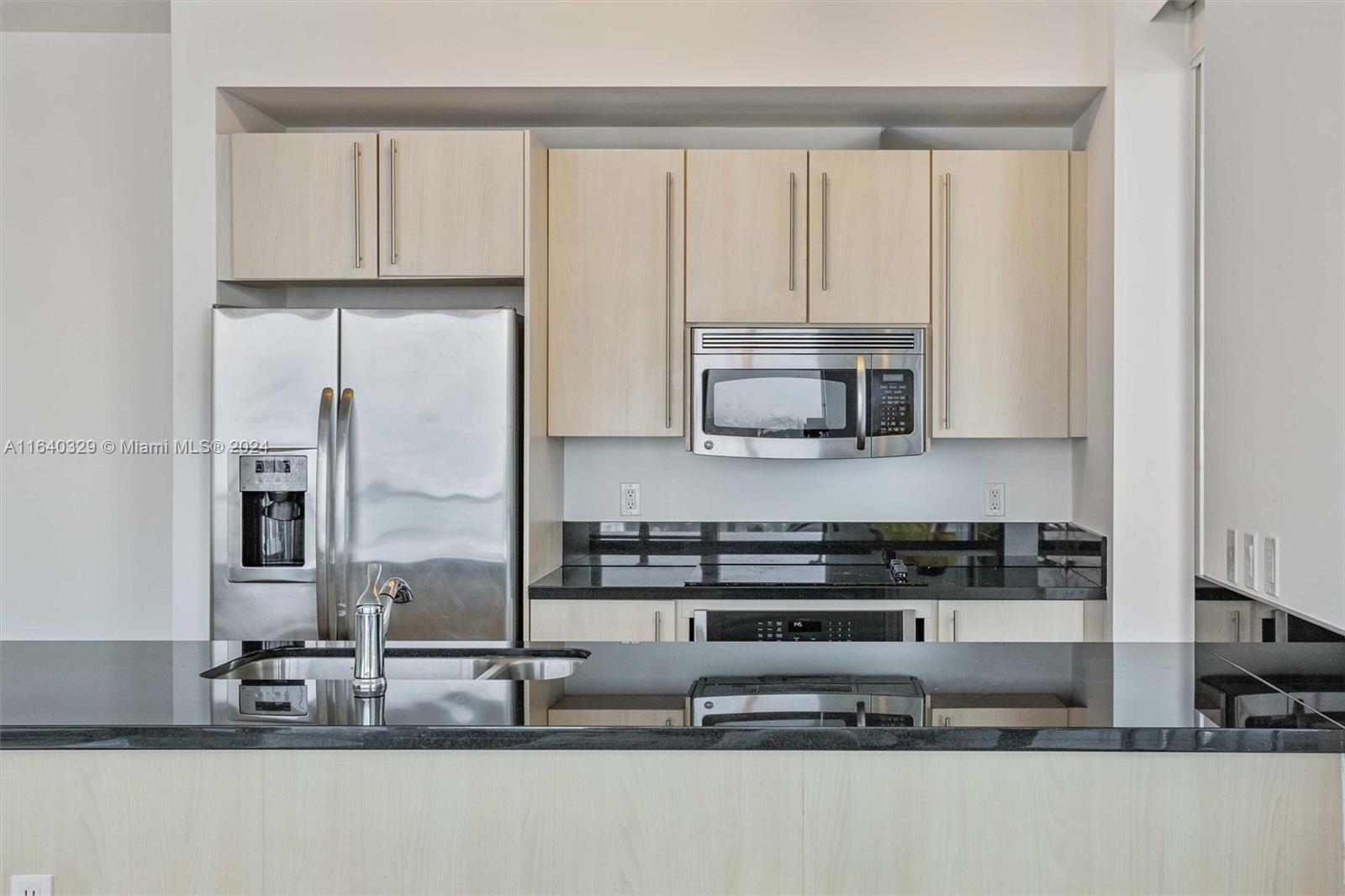 1111 Southwest 1st Avenue, Unit 3014N Miami, FL 33130 - Photo 8 of 36 a kitchen with stainless steel appliances granite countertop a sink a stove and a microwave