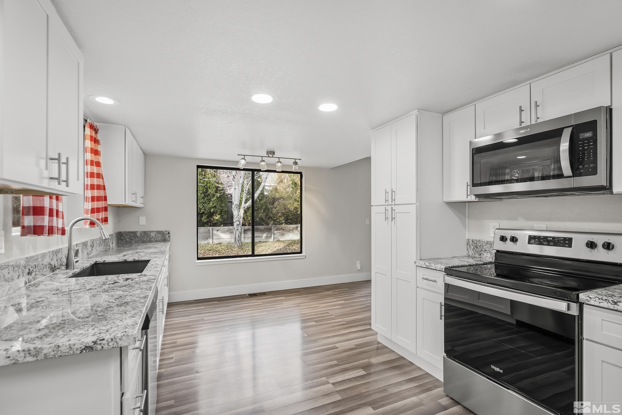 5651 West Rainbow Ridge Court Reno, NV 89523 - Photo 8 of 26 a kitchen with stainless steel appliances granite countertop a stove microwave and sink