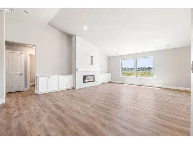 a view of an empty room with window and wooden floor