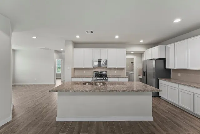 a large kitchen with stainless steel appliances kitchen island a large counter top and a stove top oven