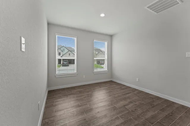 an empty room with wooden floor and windows