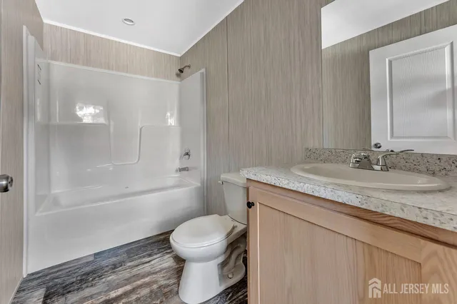 a bathroom with a granite countertop sink a toilet and shower