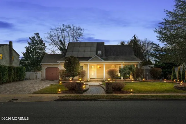 a front view of a house with a garden and trees