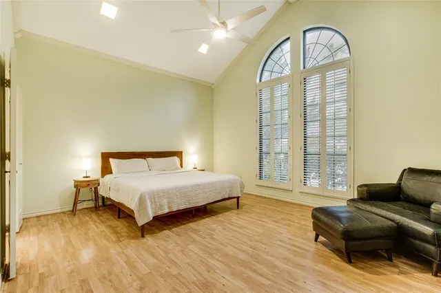 a spacious bedroom with a bed a mirror on dresser and a large window