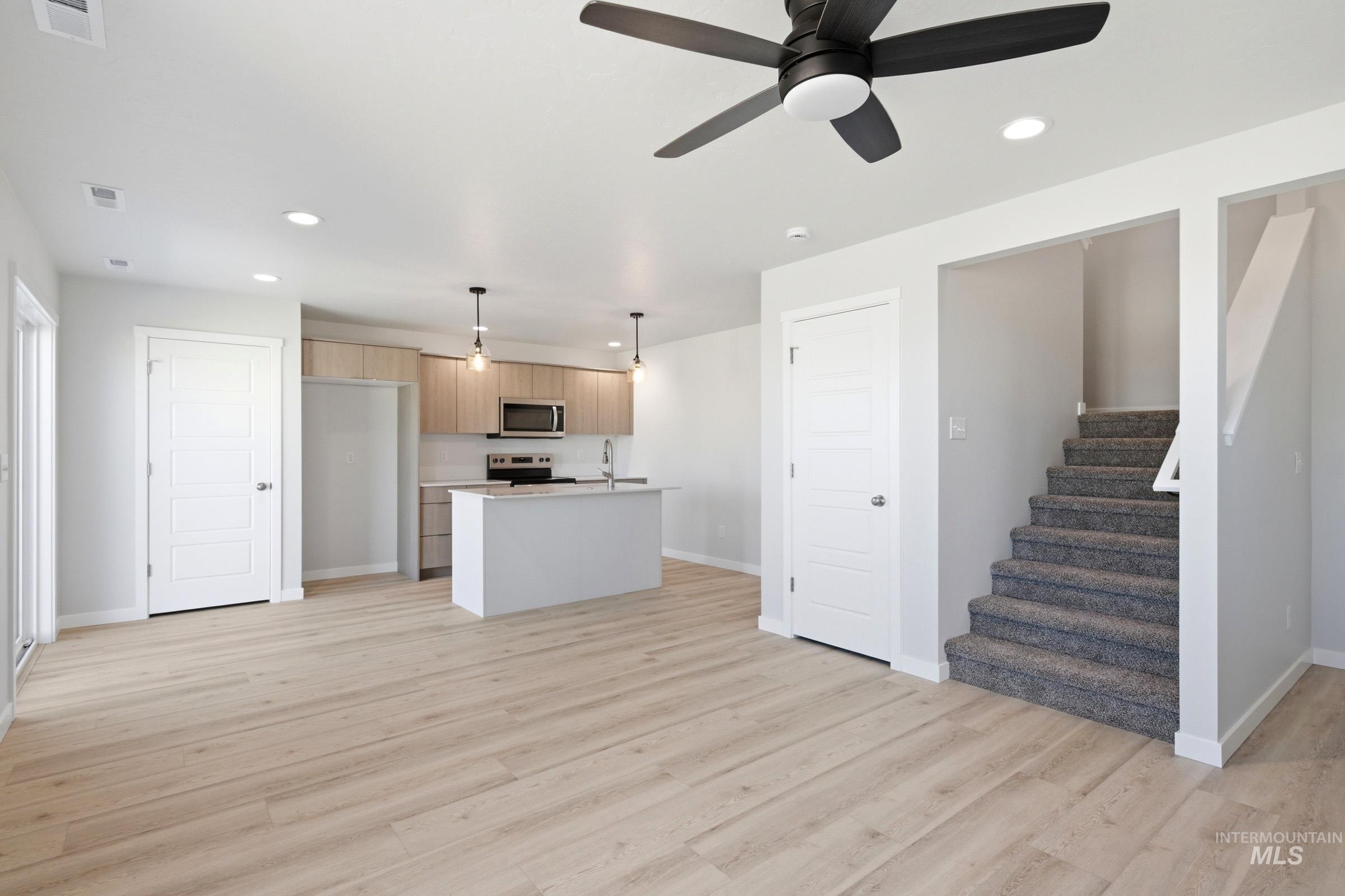 10812 Rutland Street Caldwell, ID 83605 - Photo 11 of 21 Open-concept living space featuring wood-finish flooring, a modern kitchen with a central island, recessed lighting, and a contemporary ceiling fan