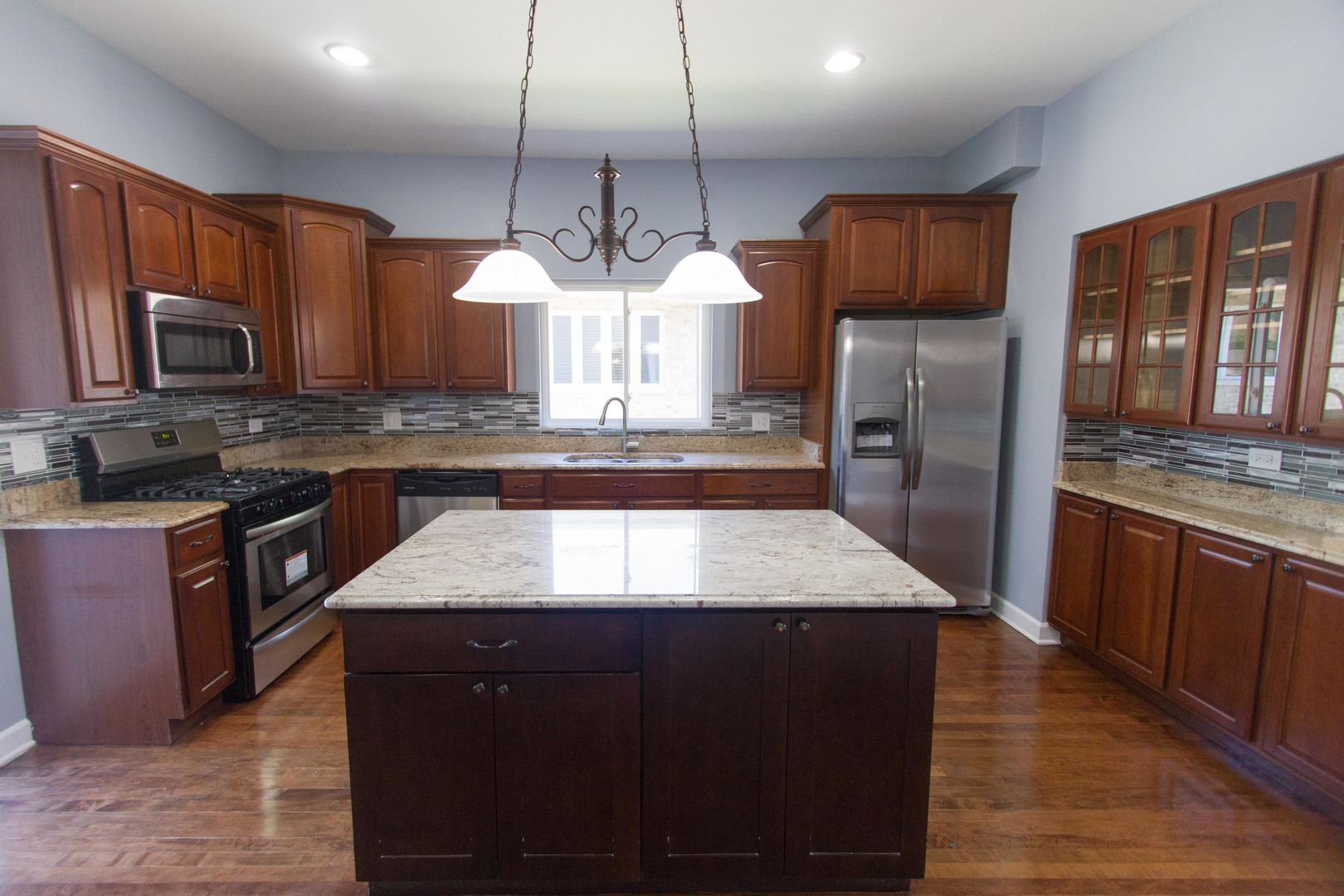 6519 28th Street Berwyn, IL 60402 - Photo 11 of 28 a kitchen with kitchen island granite countertop wooden cabinets a refrigerator a sink a stove and a wooden floors