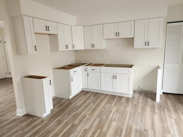 a kitchen with a sink a refrigerator and white cabinets