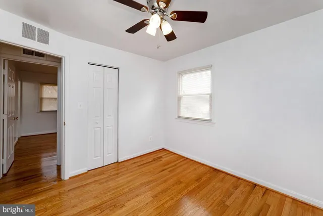 a view of empty room with wooden floor and fan
