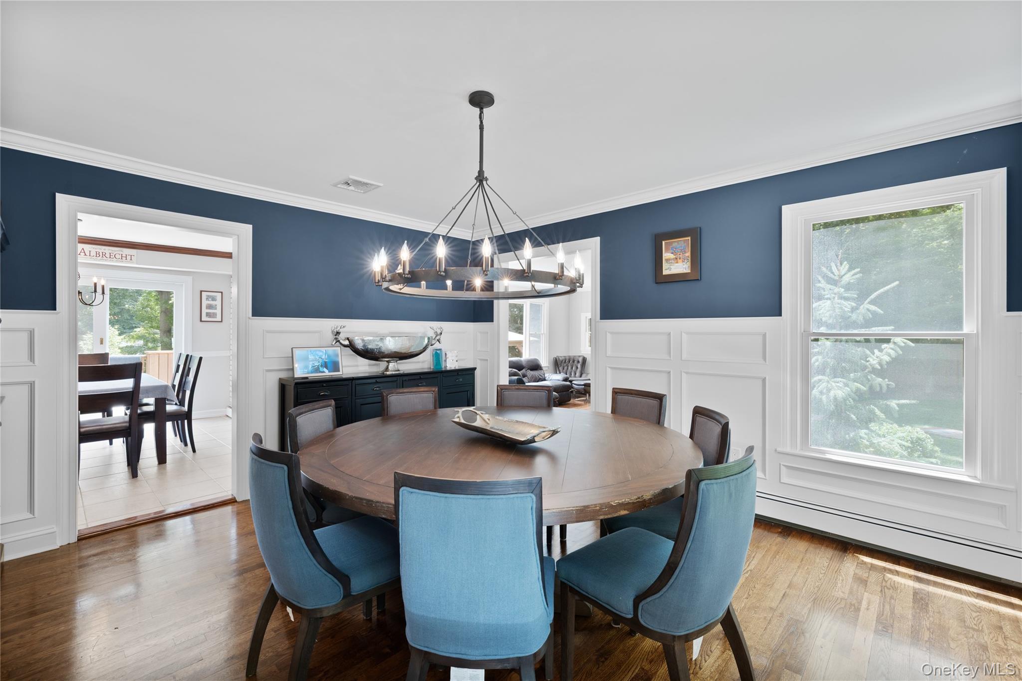 9 Three Sisters Road St. James, NY 11780 - Photo 3 of 36 Dining room wood-finish flooring, white wainscoting, and a prominent circular chandelier