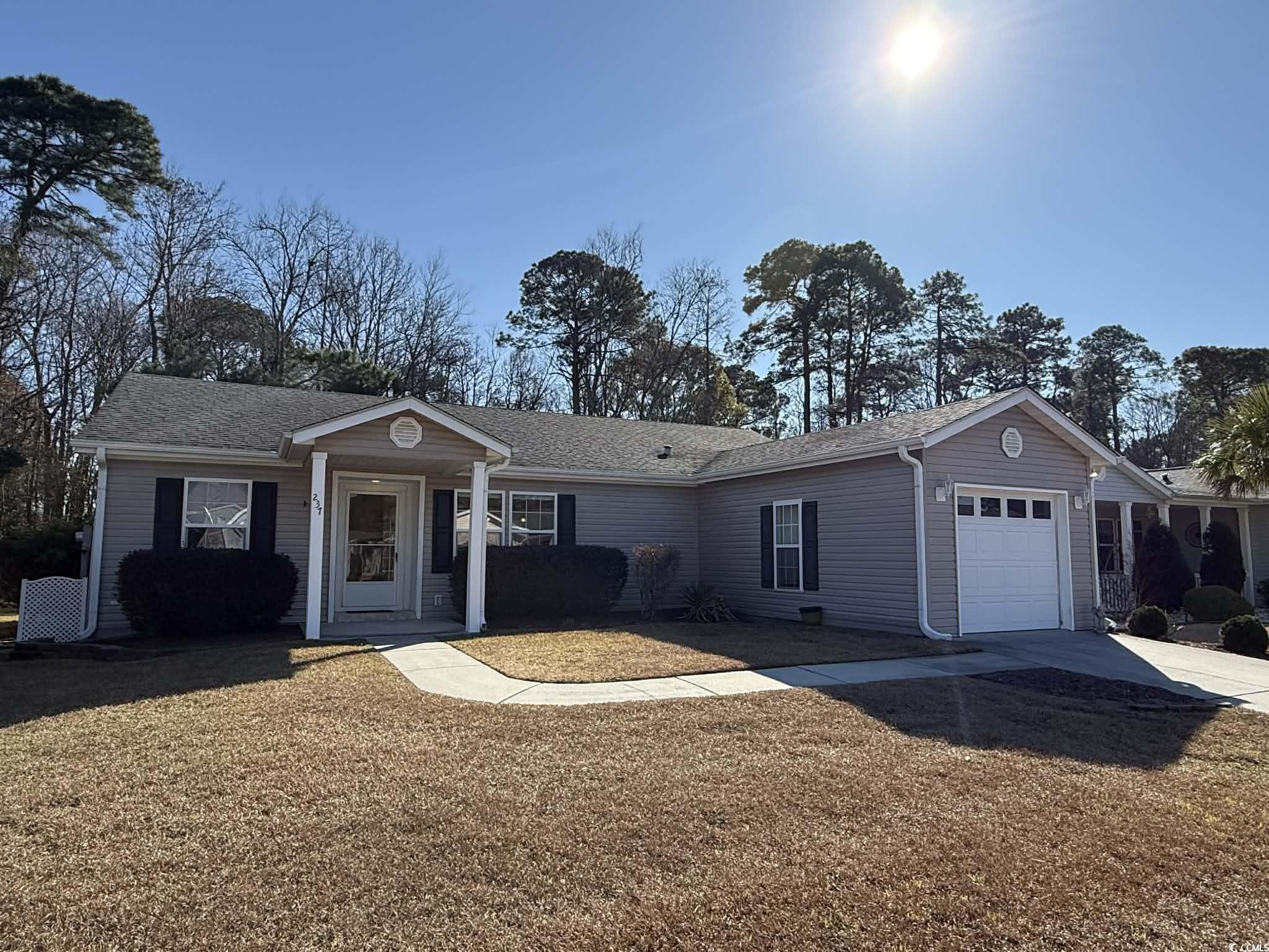 Ranch-style house featuring a front lawn, an attached garage, a shingled roof, and driveway