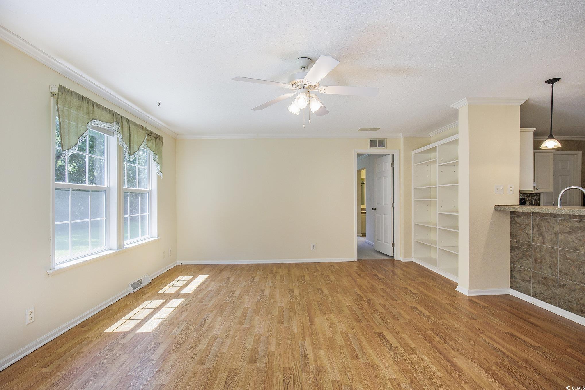 237 Wellspring Drive Conway, SC 29526 - Photo 13 of 33 Unfurnished living room featuring ornamental molding, light wood-style floors, built in shelves, and a ceiling fan