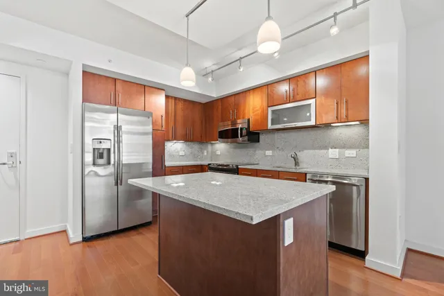 a kitchen with stainless steel appliances granite countertop a sink a refrigerator and a stove top oven