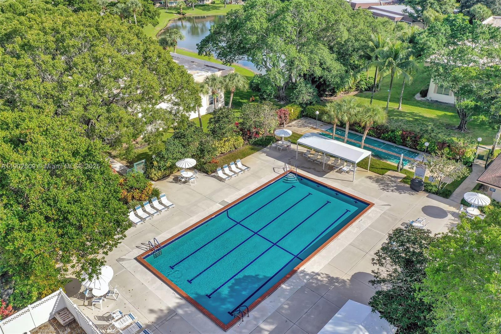 3980 Oaks Clubhouse Drive, Unit 409 Pompano Beach, FL 33069 - Photo 3 of 70 Resort-style amenities include a sparkling lap pool with plenty of lounge space, shaded seating areas, and beautifully landscaped surroundings — perfect for a morning swim or an afternoon in the sun.