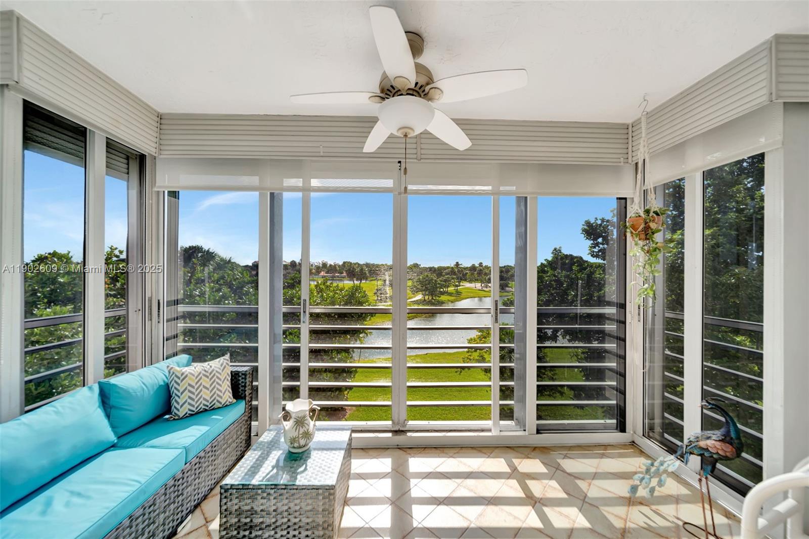 3980 Oaks Clubhouse Drive, Unit 409 Pompano Beach, FL 33069 - Photo 39 of 70 a living room with furniture a chandelier and a floor to ceiling window