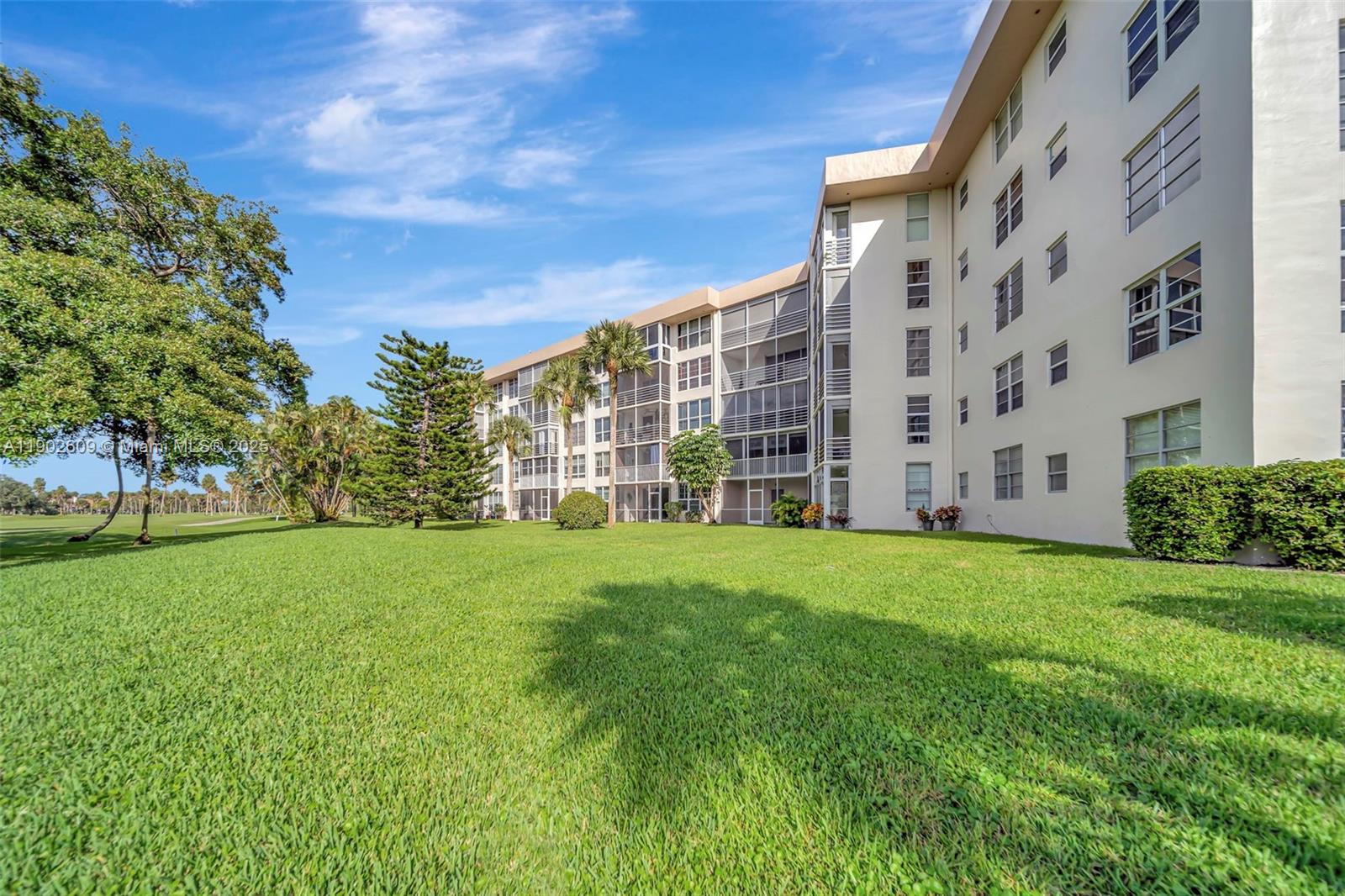 3980 Oaks Clubhouse Drive, Unit 409 Pompano Beach, FL 33069 - Photo 53 of 70 front view of a building with a big yard