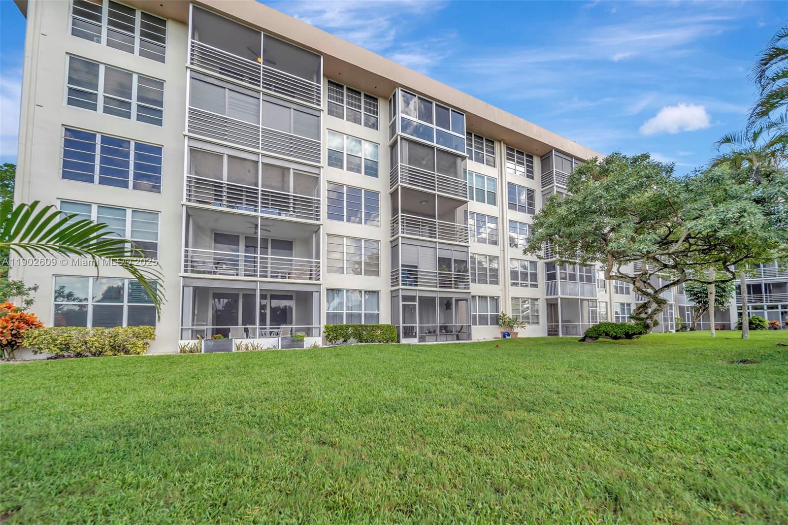 3980 Oaks Clubhouse Drive, Unit 409 Pompano Beach, FL 33069 - Photo 55 of 70 a large building with a yard in front of it