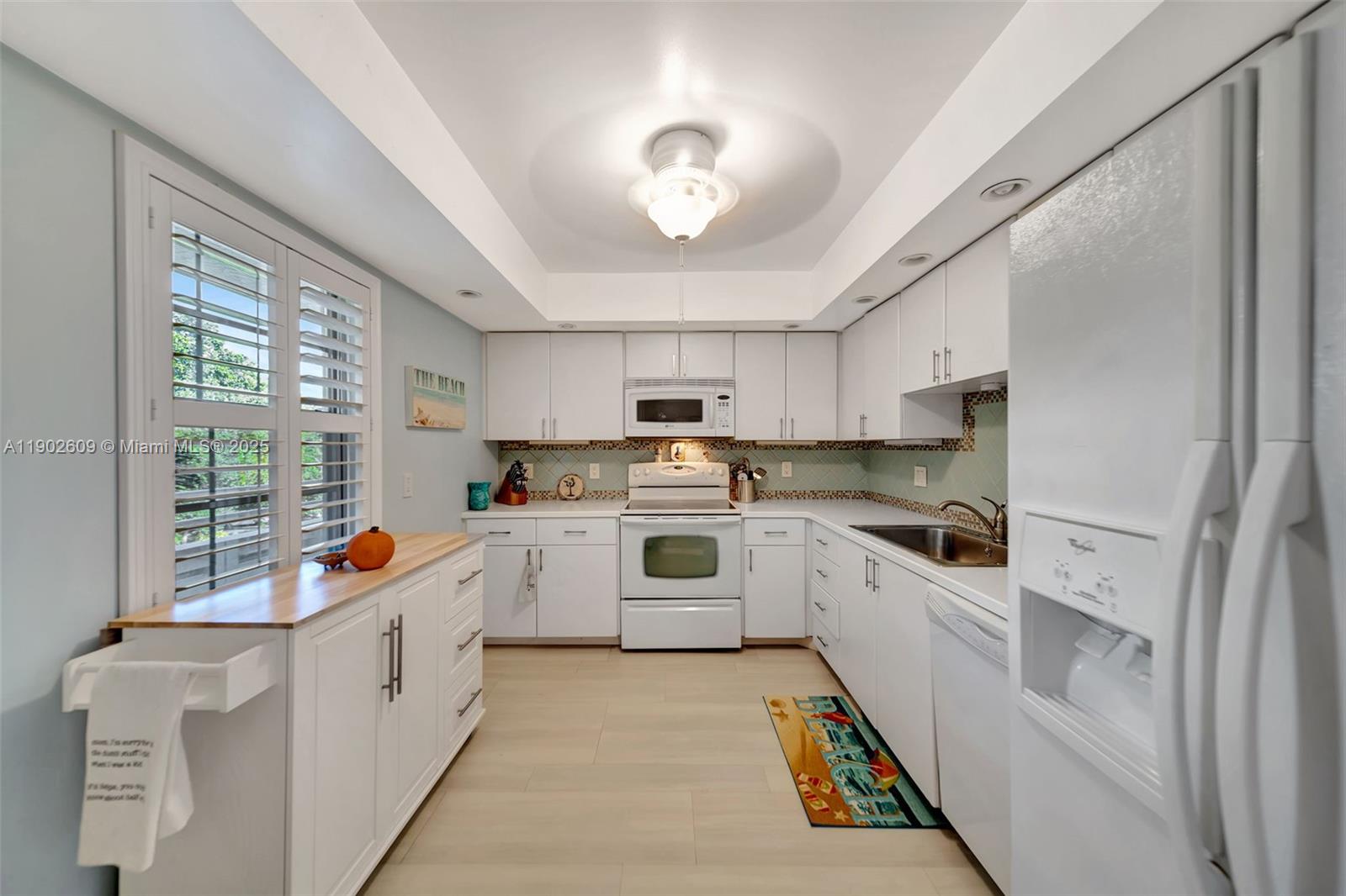3980 Oaks Clubhouse Drive, Unit 409 Pompano Beach, FL 33069 - Photo 9 of 70 a kitchen with white cabinets and white appliances