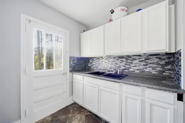 a kitchen with granite countertop white cabinets and sink