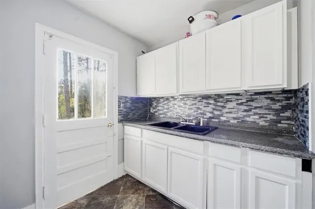 a kitchen with granite countertop white cabinets and sink