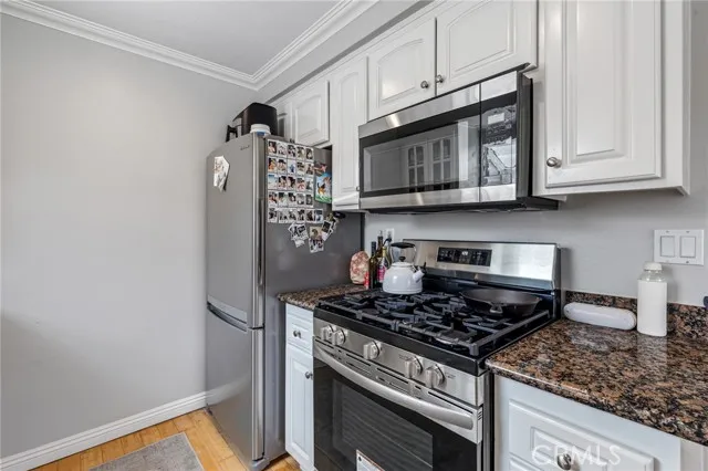 209 13th Street, Unit D Huntington Beach, CA 92648 - Photo 13 of 34 a kitchen with stainless steel appliances granite countertop a stove and a microwave