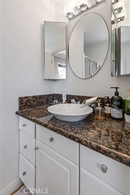 209 13th Street, Unit D Huntington Beach, CA 92648 - Photo 17 of 34 a bathroom with a granite countertop sink and a mirror