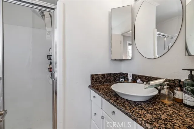 209 13th Street, Unit D Huntington Beach, CA 92648 - Photo 18 of 34 a bathroom with a granite countertop sink a mirror a vanity and a shower