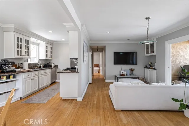 209 13th Street, Unit D Huntington Beach, CA 92648 - Photo 5 of 34 a view of living room kitchen with stainless steel appliances granite countertop a stove a sink dishwasher a microwave oven and a dining table with wooden floor