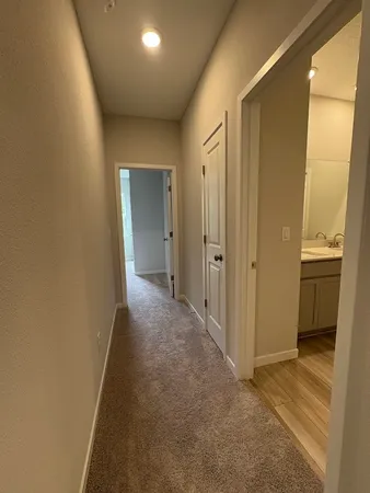 a view of a hallway with wooden floor and a bathroom