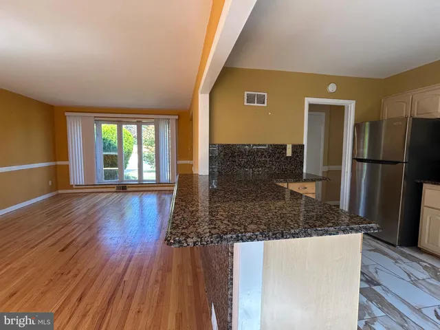 a kitchen with stainless steel appliances granite countertop a refrigerator and wooden floor