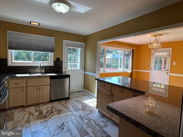 a large kitchen with kitchen island granite countertop a large window and stainless steel appliances
