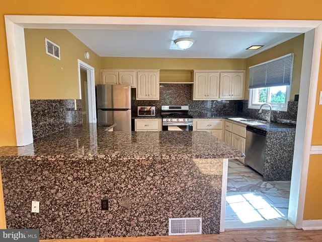 a kitchen with stainless steel appliances kitchen island granite countertop a stove a sink and a microwave