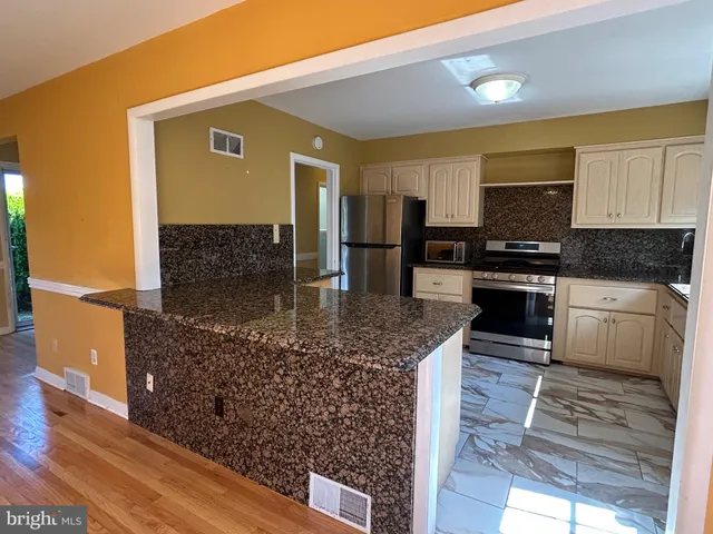 a kitchen with stainless steel appliances granite countertop a stove a sink and a microwave