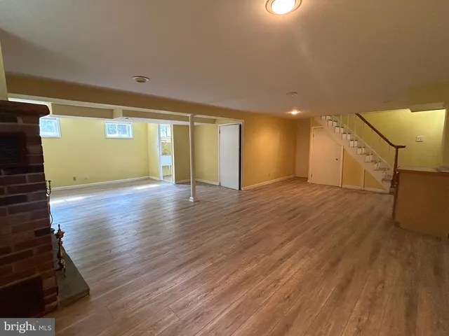 a view of an empty room with wooden floor and a fireplace