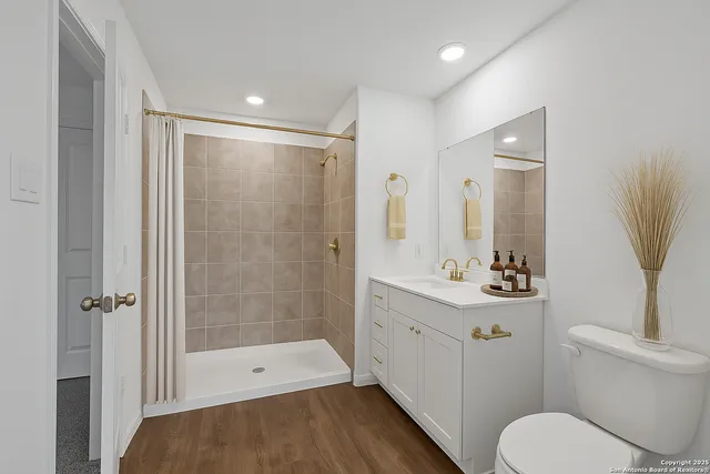 a bathroom with a sink a toilet a mirror and shower