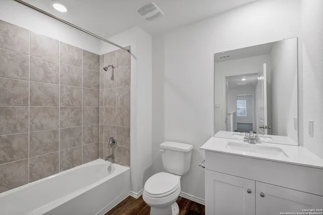 a bathroom with a bathtub shower sink mirror vanity and toilet
