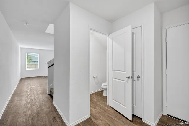 a view of a hallway with wooden floor and closet area
