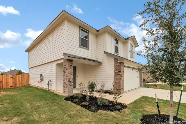 a view of a white house next to a yard with big trees