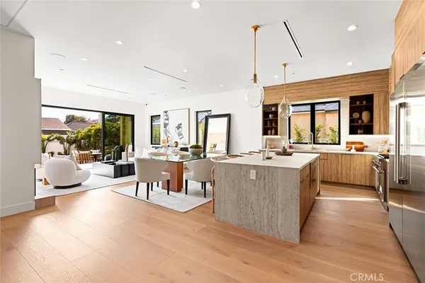 a kitchen with stainless steel appliances kitchen island a table chairs in it and wooden floors