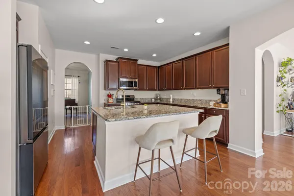 a kitchen with granite countertop wooden floors and white stainless steel appliances