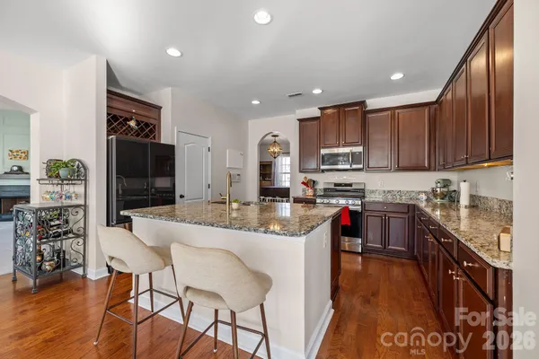 a kitchen with stainless steel appliances granite countertop wooden cabinets a refrigerator a stove a sink and a island