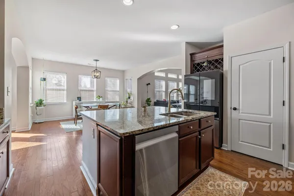 a kitchen with stainless steel appliances granite countertop a refrigerator a sink dishwasher and a stove with wooden floor