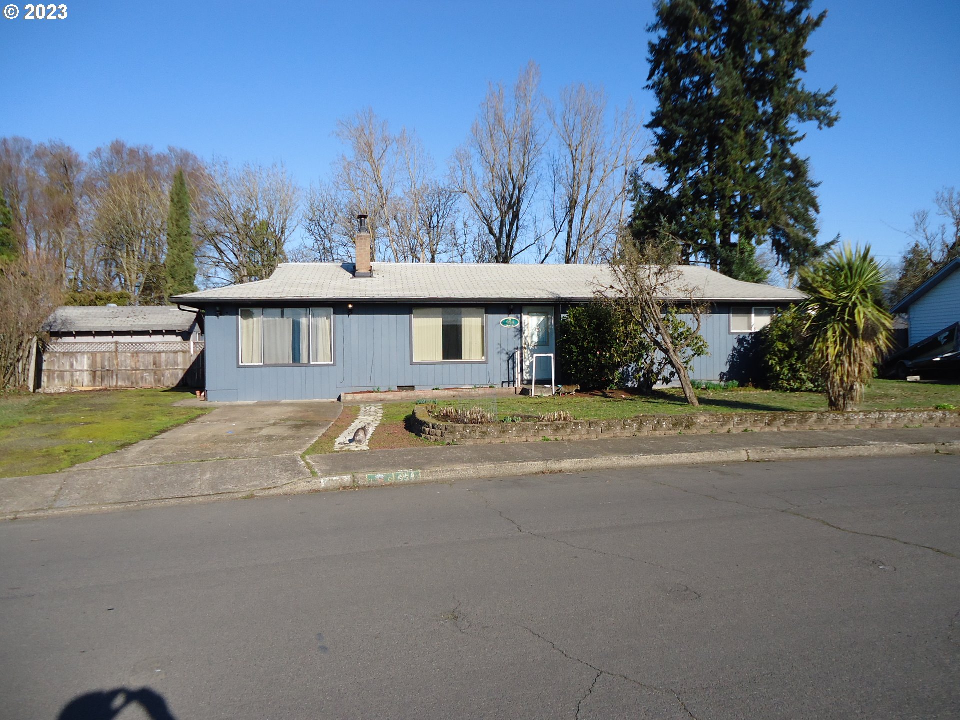 a front view of a house with a garden and trees