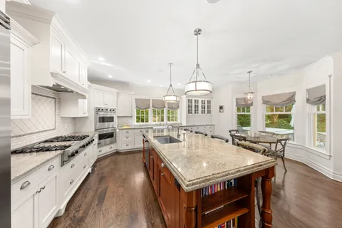 a kitchen with stainless steel appliances granite countertop a stove a kitchen island a stove and a wooden floors