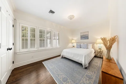 a bedroom with a bed lamp and a large window with wooden floor